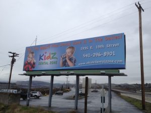 Billboard advertising design Kidz Dental Zone in The Dalles with two children and contact information including address, phone, and website